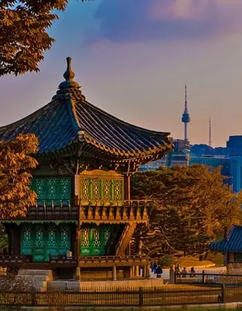 Korea_350-450_Seoul_Palace Traditional Korean pavilion at Deoksugung Palace with N Seoul Tower rising in the background, blending historic architecture with Seoul’s modern skyline.